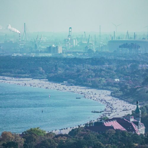 Beaches of Sopot and Gdańsk. In the background, shipyard cranes and a football stadium.